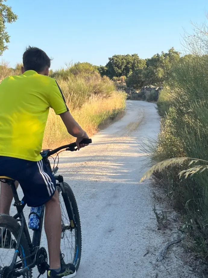 Niño en bicicleta contemplando un camino de tierra durante una ruta por la Sierra de San Pedro desde Casa Rural La Vega.